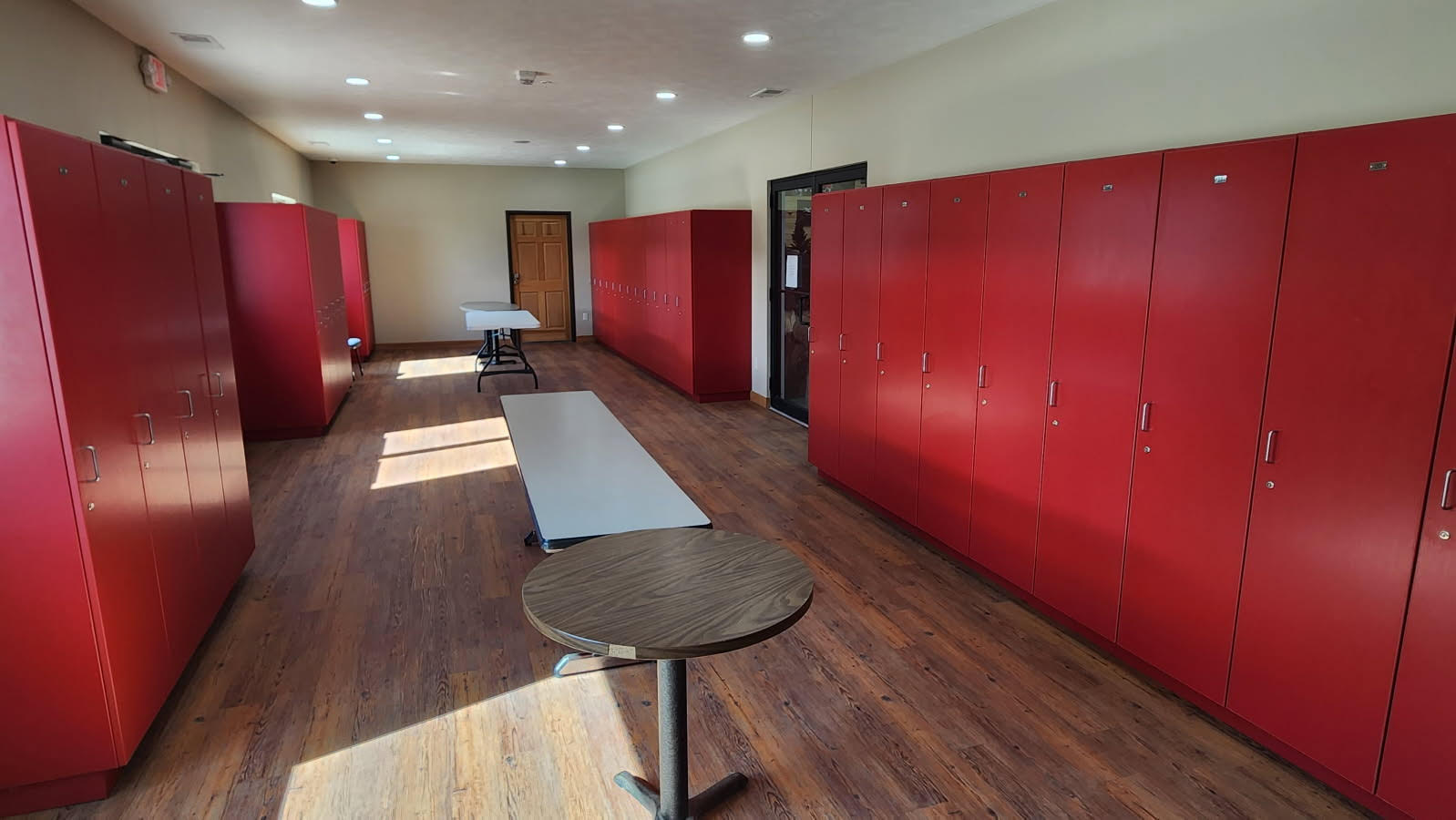 Locker room with red storage lockers, benches, and tables