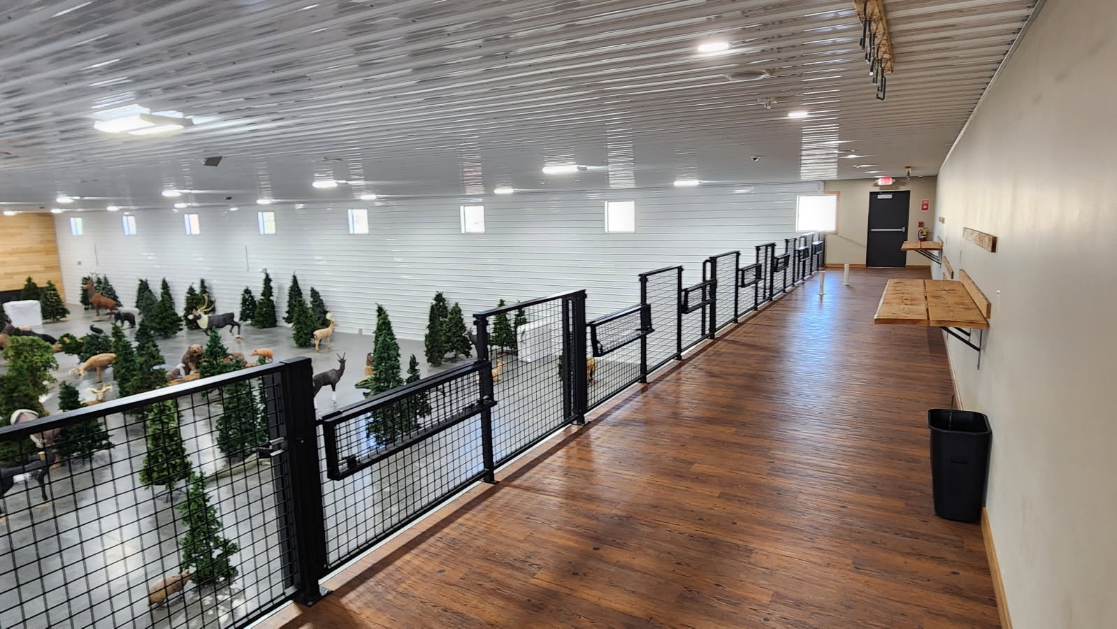 Upstairs mezzanine walkway with black mesh railing overlooking the 3D archery course